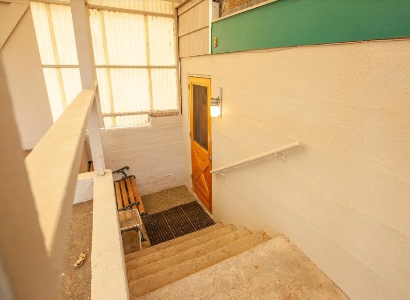 A wooden door is at the end of a staircase.